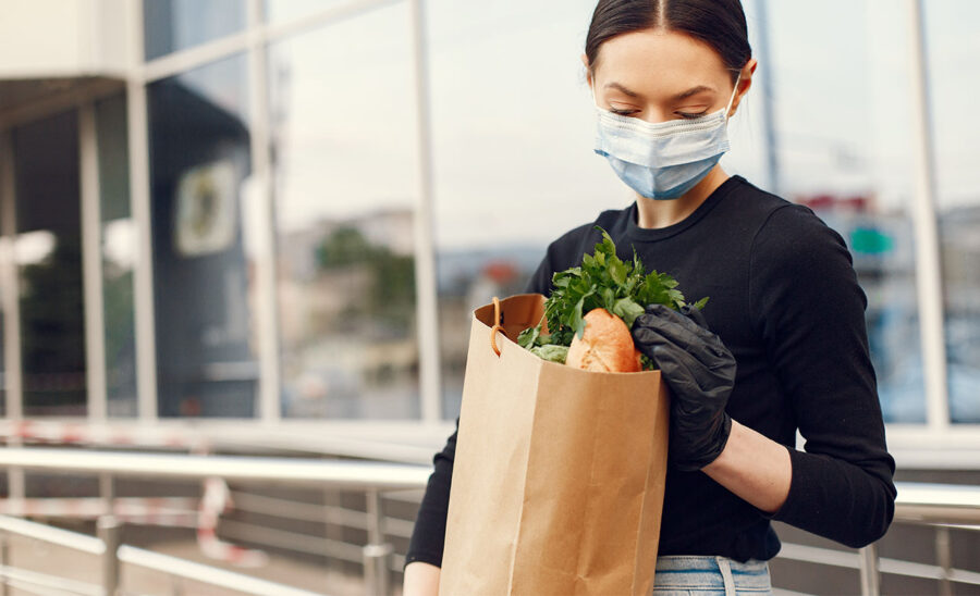 Femme tenant un sac de courses en papier d'épicerie rempli de légumes frais