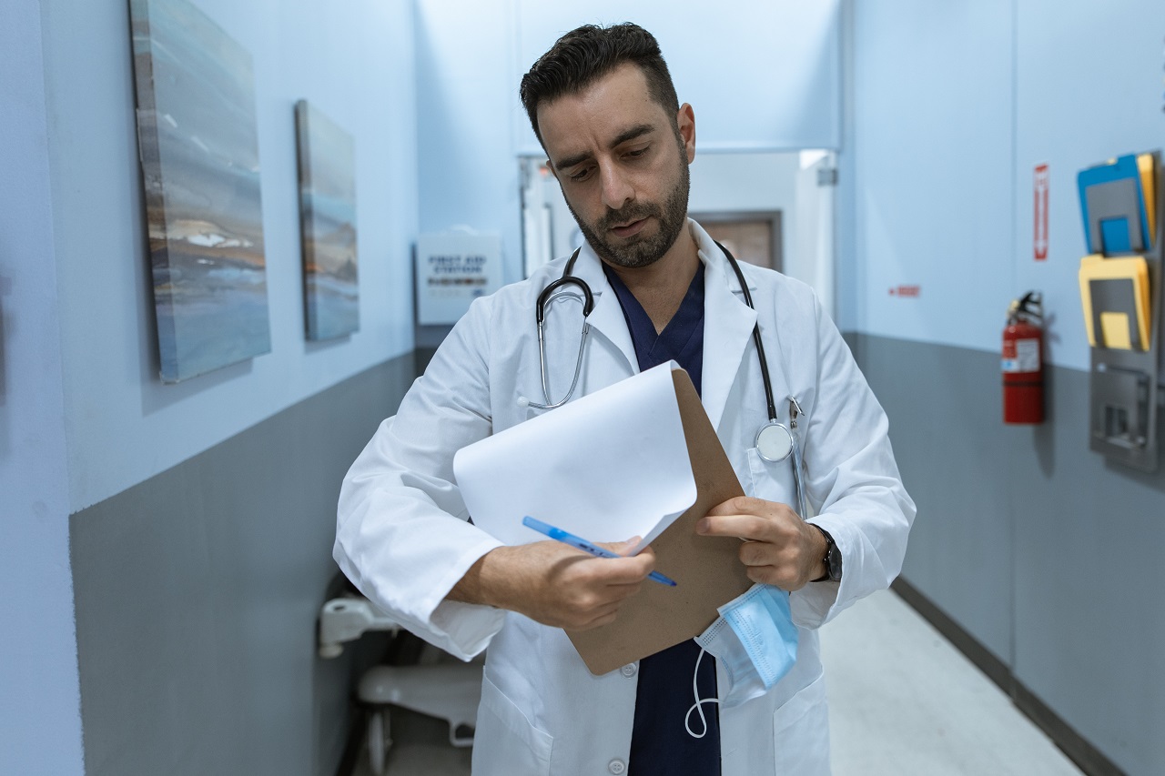 Un Médecin entrain de consulter une fiche médicale d'un patient dans le couloir d'un hôpital.