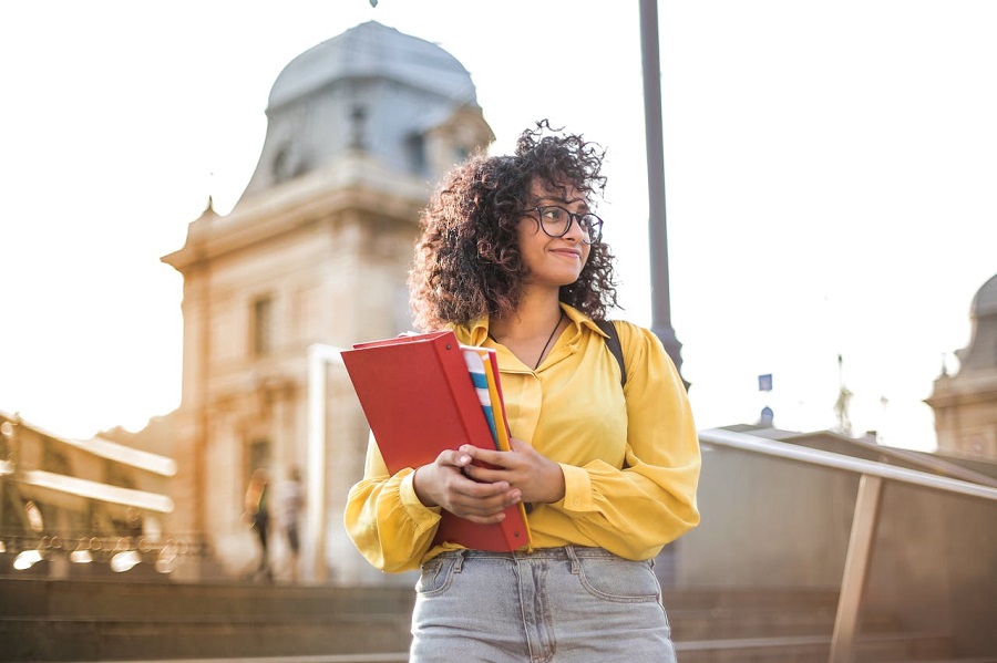 femme-en-veste-jaune-tenant-un-livre-rouge