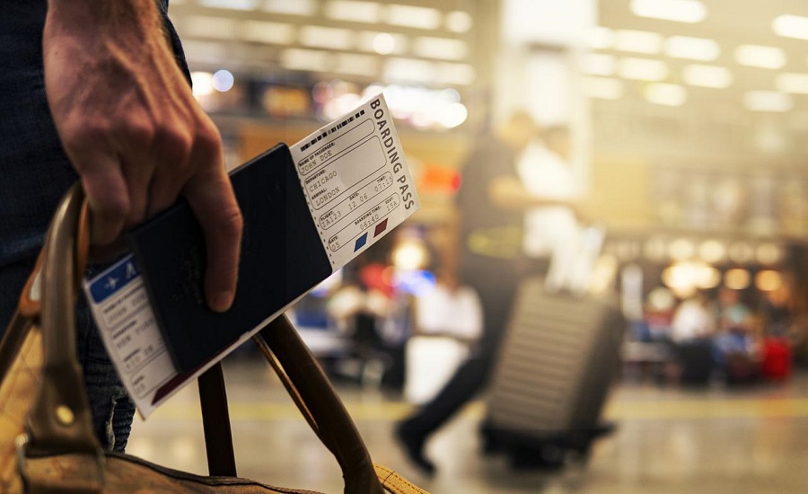 Une main tenant un passeport, un billet d'avion, ainsi qu'un bagage
